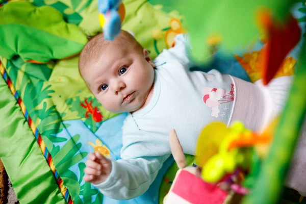 Cute adorable newborn baby playing on colorful toy gym — Stock Photo, Image