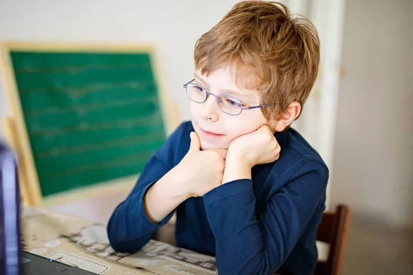 Мальчик в очках делает домашнее задание по компьютеру — стоковое фото