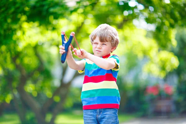 Little kid boy shooting wooden slingshot — Stock Photo, Image