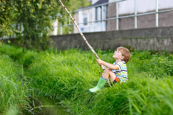 Kleiner Junge angelt mit selbstgebastelter Angelrute auf Fluss — Stockfoto