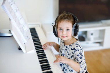 Güzel küçük çocuk kız oturma odası veya müzik okulu piyano
