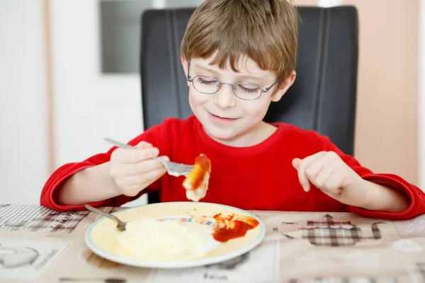 Adorable little school boy eating potato mash and chicken breast indoor — Stock Photo, Image