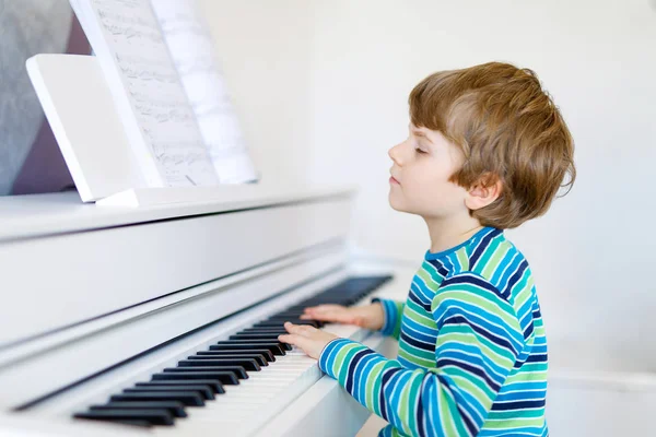 Красивый маленький мальчик играет на пианино в гостиной или музыкальной школе — стоковое фото