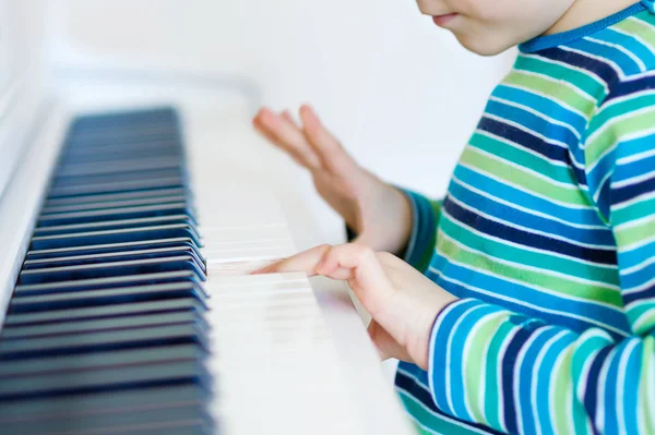Menino pequeno bonito tocando piano na sala de estar ou escola de música — Fotografia de Stock