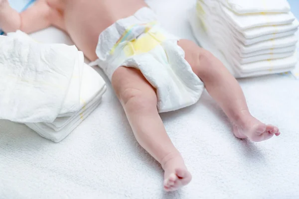 Feet of newborn baby on changing table with diapers — Stock Photo, Image