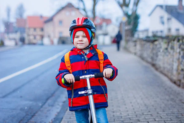 Cute little preschool kid boy riding on scooter riding to school. — Stock Photo, Image
