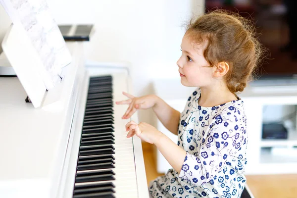 Schönes kleines Mädchen, das im Wohnzimmer oder in der Musikschule Klavier spielt — Stockfoto