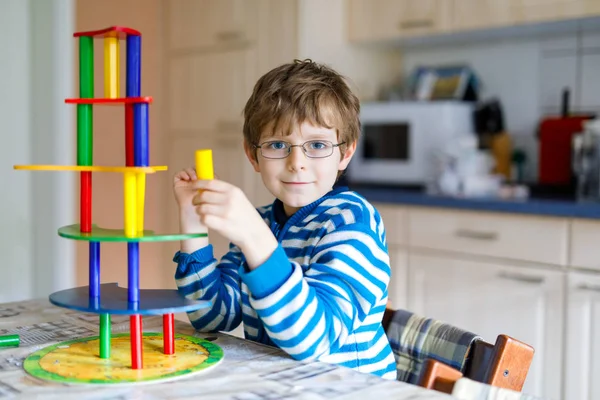 Niño con gafas jugando con un montón de bloques de madera de colores juego interior — Foto de Stock