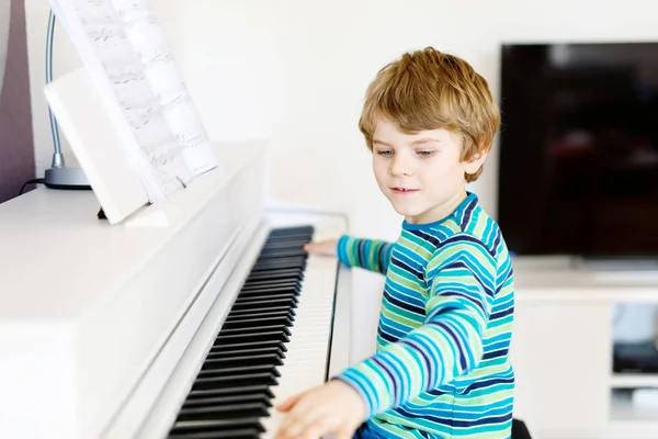 Beautiful little kid boy playing piano in living room or music school — Stock Photo, Image