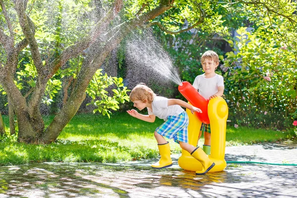 Dos niños pequeños jugando con manguera de jardín y agua en verano —  Fotos de Stock