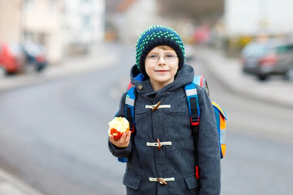 Kleiner Junge mit Brille läuft von der Schule und isst Apfel — Stockfoto