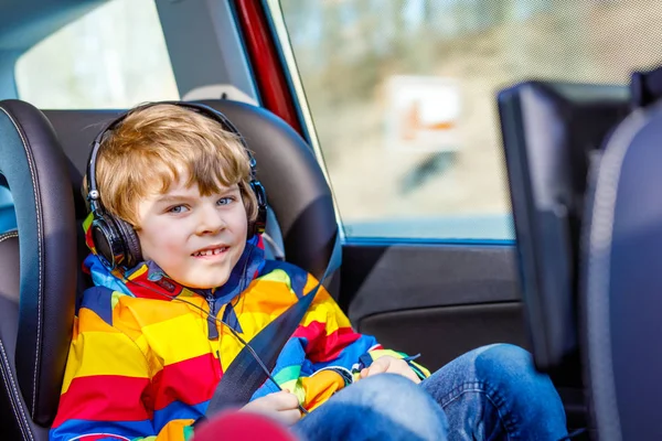 Szőke kisgyerek fiú néz TV-n vagy dvd-val fejhallgató során hosszú autóútra — Stock Fotó