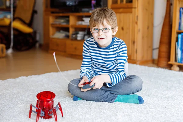 Активный школьник в очках играет с игрушкой-роботом — стоковое фото