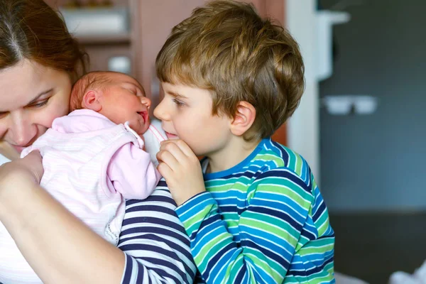 Beetje kid jongen pasgeboren zus kussen. Moeder bedrijf baby op arm. — Stockfoto