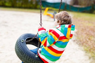 Komik çocuk dışarıda zincirli salıncakla eğleniyor.