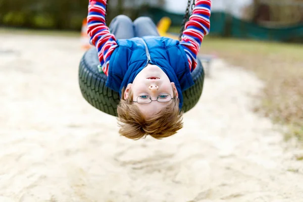 Funny kid boy having fun with chain swing on outdoor playground — Stock Photo, Image