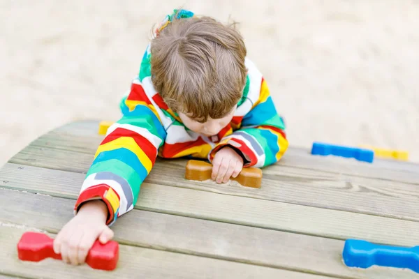 Felice ragazzo biondo che si diverte e si arrampica sul parco giochi all'aperto — Foto Stock