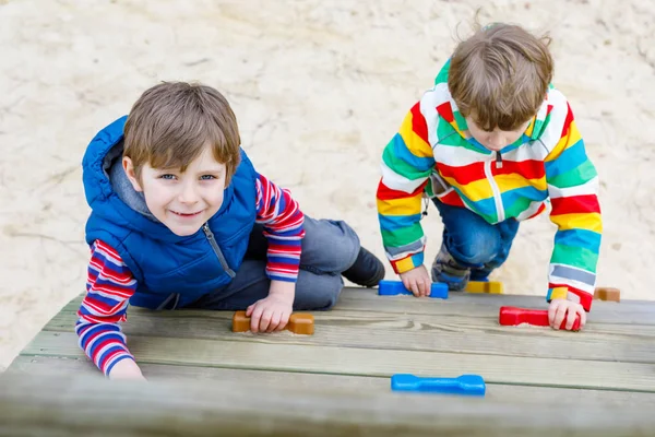 Два маленьких мальчика веселятся и лазают по открытой детской площадке — стоковое фото