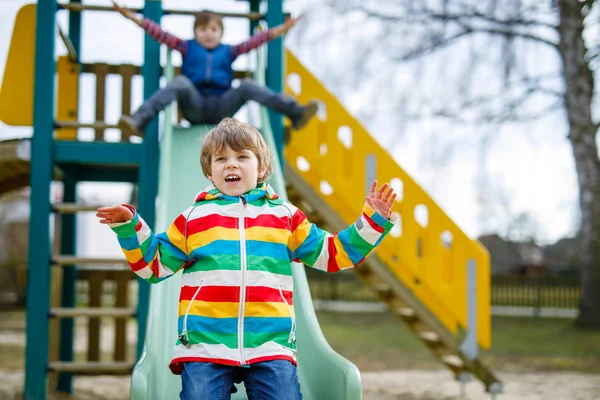 Two little kid boys having fun and sliding on outdoor playground — Stock Photo, Image