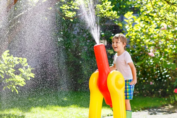 Menino brincando com uma mangueira de jardim e água — Fotografia de Stock