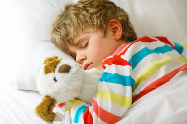 Mały blond chłopiec w kolorowe ubrania nocne śpi — Zdjęcie stockowe
