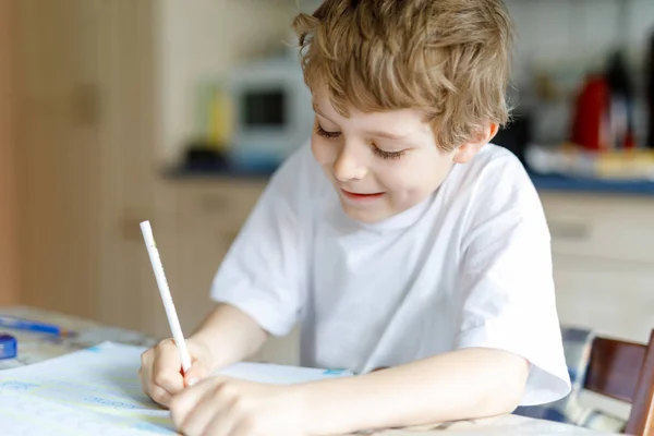 Gelukkig schoolkind jongen thuis het maken van huiswerk — Stockfoto