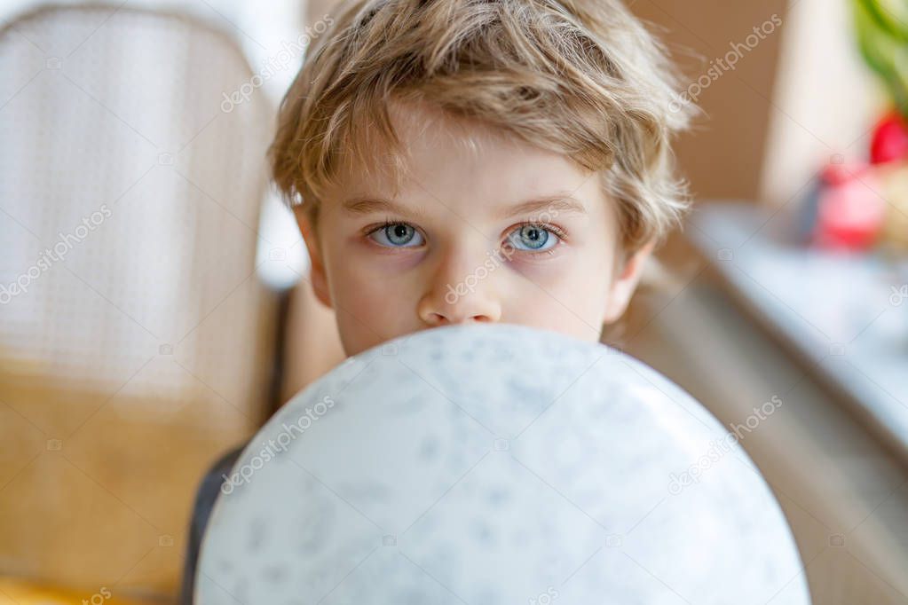 Little blond preschool kid boy with air balloon ball