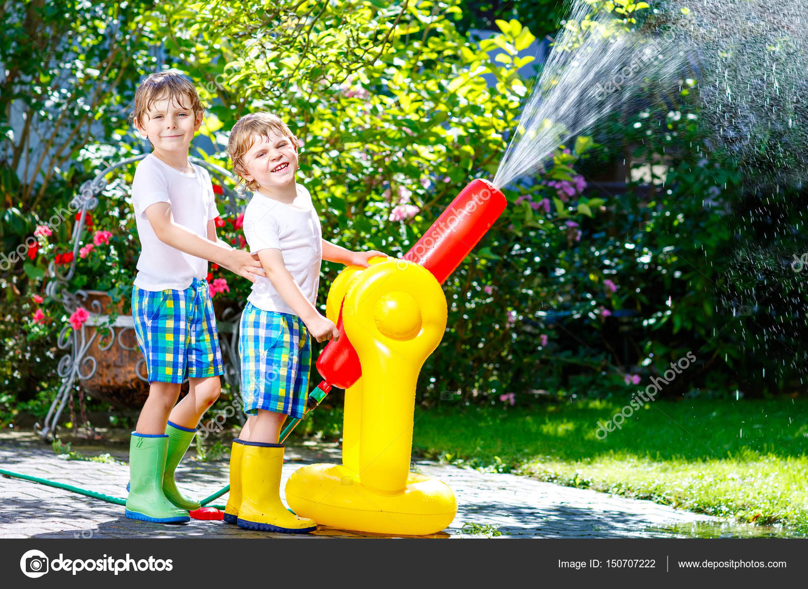 Two little kids boys playing with a garden hose water sprinkler — Stock Photo © romrodinka