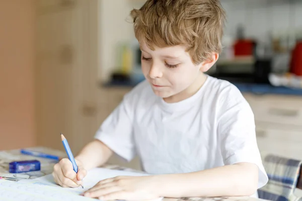 Glücklicher Schuljunge zu Hause, der Hausaufgaben macht — Stockfoto