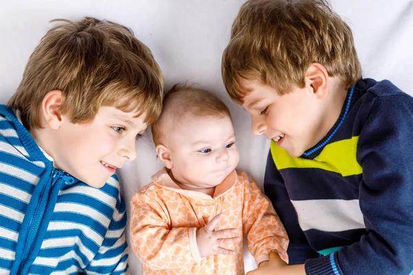 Двоє щасливих маленьких дошкільнят хлопчиків з новонародженою дівчинкою — стокове фото