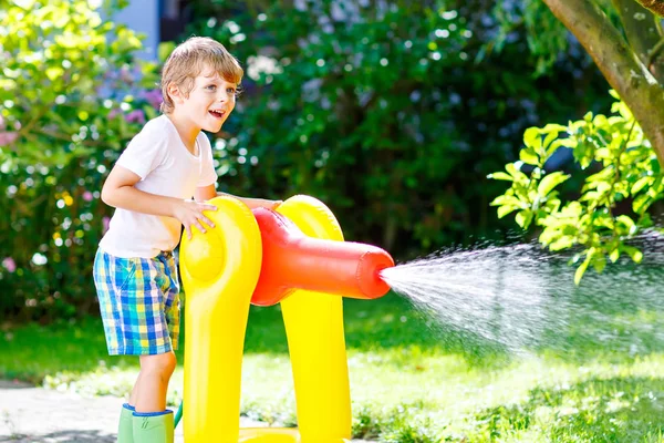 Little kid boy playing with a garden hose water sprinkler — Stock Photo, Image