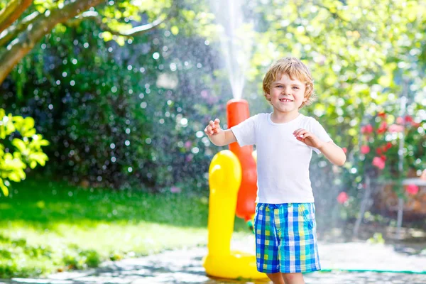 Menino brincando com um aspersor de água de mangueira de jardim — Fotografia de Stock