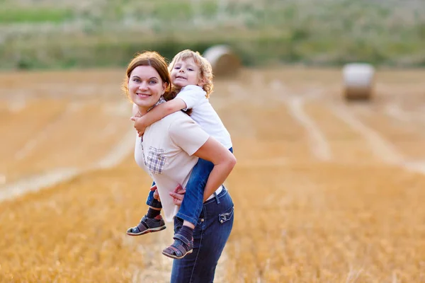 Mutter hält Jungen im Sommer auf dem Weizenfeld auf Arm — Stockfoto