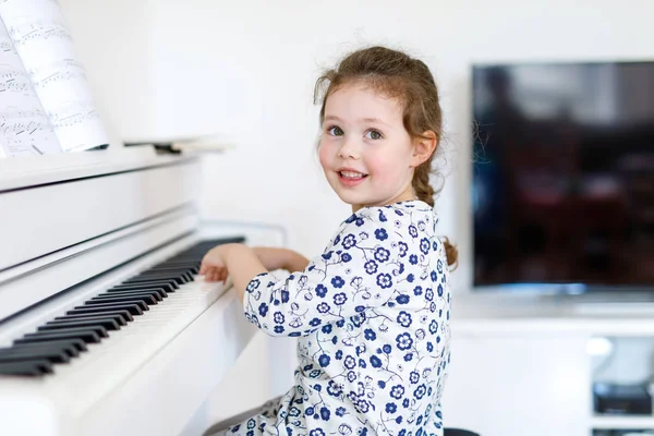 Красива маленька дівчинка грає на піаніно у вітальні або музичній школі — стокове фото