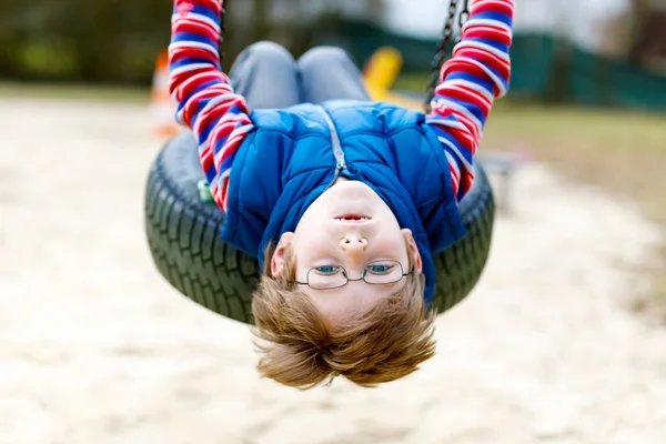 Funny kid boy having fun with chain swing on outdoor playground — Stock Photo, Image
