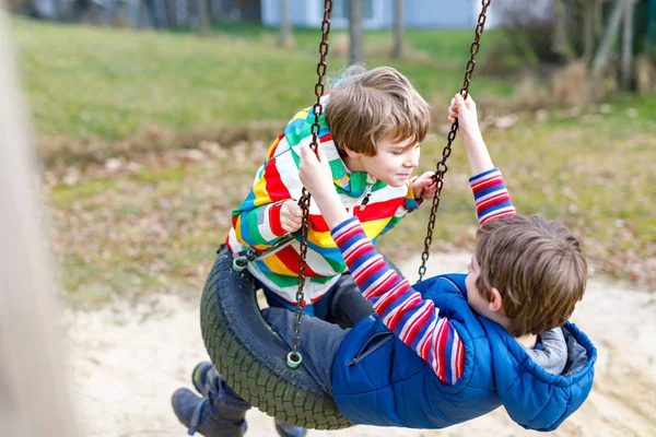 Twee kleine jongen jongens plezier met ketting swing op speelplaats — Stockfoto