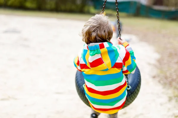 Engraçado garoto menino se divertindo com corrente swing no playground ao ar livre — Fotografia de Stock