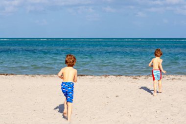 İki küçük çocuk tropik sahilde eğleniyor.