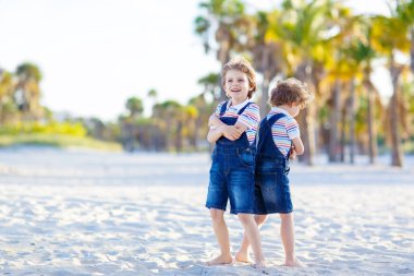 İki küçük çocuk tropik sahilde eğleniyor.