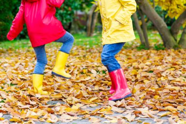 Kırmızı ve sarı lastik çizme sonbahar parkta oynayan iki küçük çocuk