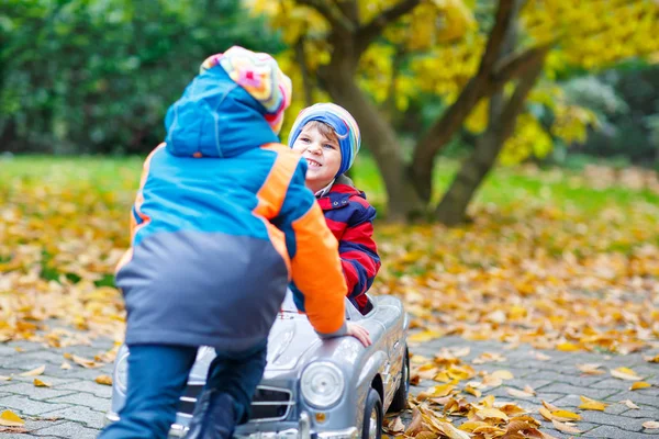 Брат толкает машину для ребенка. Счастье, веселье, отдых в осеннем парке . — стоковое фото