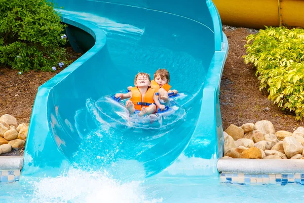 Opgewonden kinderen in waterpark rijden op dia met vlotter — Stockfoto