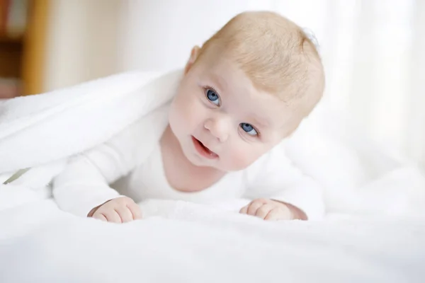 Babymädchen mit weißem Handtuch oder Wintermantel im weißen, sonnigen Schlafzimmer — Stockfoto