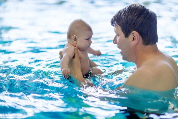 Glad medelålders fader simning med söt bedårande baby i poolen. — Stockfoto