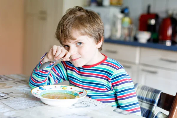 Adorable little school boy eating vegetable soup indoor. — Stock Photo, Image