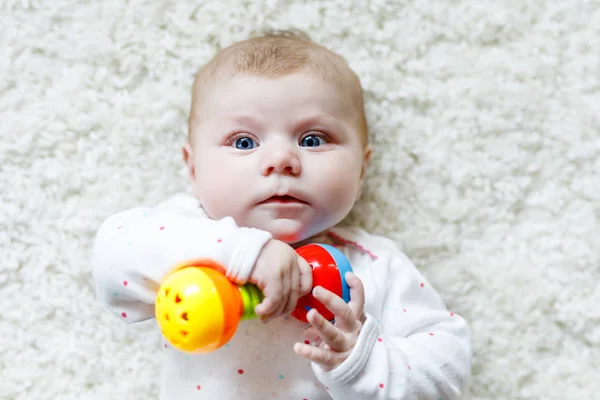 Linda niña jugando con colorido juguete sonajero —  Fotos de Stock