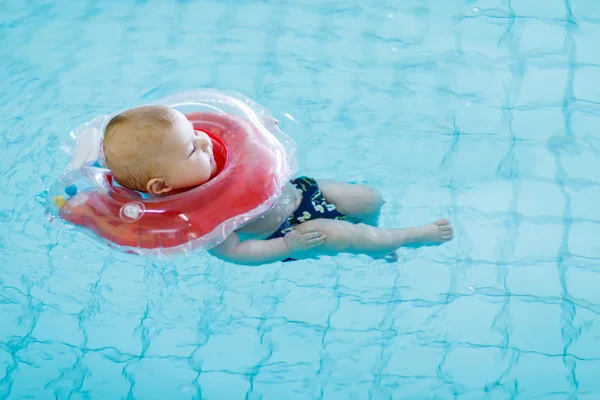 Carino bambino che impara a nuotare con anello di nuoto in una piscina coperta — Foto Stock