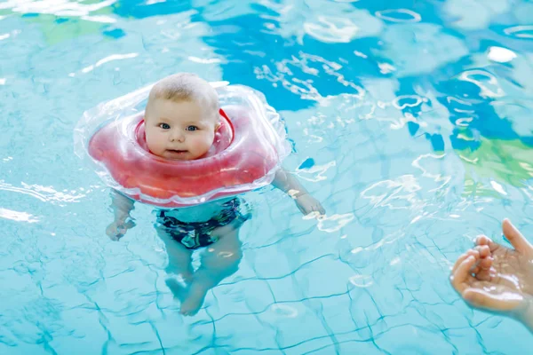 Lindo bebé pequeño aprendiendo a nadar con anillo de natación en una piscina cubierta — Foto de Stock