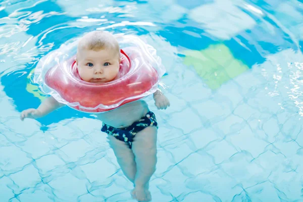 Lindo bebé pequeño aprendiendo a nadar con anillo de natación en una piscina cubierta — Foto de Stock