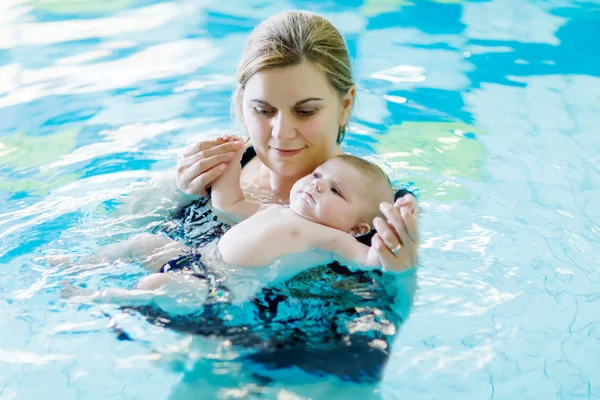 Gelukkig middelbare leeftijd moeder zwemmen met schattige schattige baby in zwembad. — Stockfoto